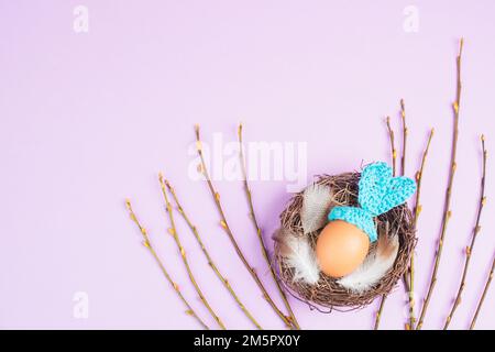 Osterhasen oder Kaninchen in einem Vogelnest, aus einem Ei und Häkelohren, Frühlingsferien, Grußkarte Stockfoto