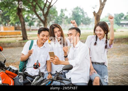 Vier glückliche High-School-Schüler Selfie zur Feier der Abschlussfeier auf dem Motorrad Stockfoto