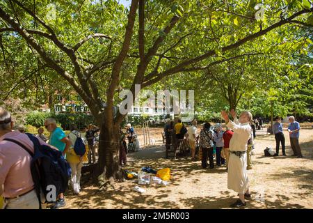 Die Menschen versammeln sich in der Nähe des Kirschbaums, der zum Gedenken an die Opfer von Hiroshima während einer Gedenkveranstaltung am Tavistock Square in London gepflanzt wurde. Stockfoto