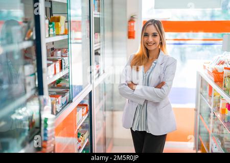 Attraktive Apothekerin in Uniform, die vor der Kamera lächelt Stockfoto