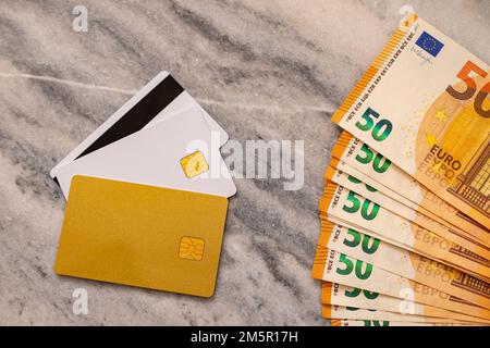 Nahaufnahme von 50 Euro-Banknoten und Bankkarten. Konzept Des Vergleichs Von Bargeld Und Non-Bargeld. Stockfoto