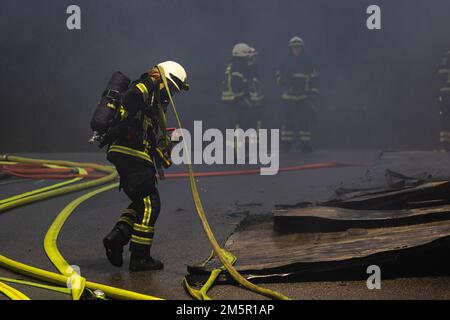 Wehr, Deutschland. 30. Dezember 2022. Ein Feuerwehrmann zieht einen Schlauch über den Tatort. Ein Brand in mehreren Gebäuden an einem Industriestandort verursachte Schäden im Wert von mehreren Millionen Euro. Die Feuerwehren waren mit etwa 160 Einsatzkräften vor Ort. Kredit: Philipp von Ditfurth/dpa/Alamy Live News Stockfoto