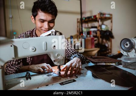 asiatischer Mann schneidet Leder mit Nähmaschine an Stockfoto