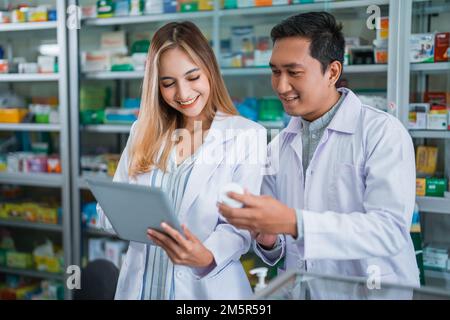 Apothekerinnen, die mit männlichen Apothekern arbeiten, prüfen die Medizin Stockfoto