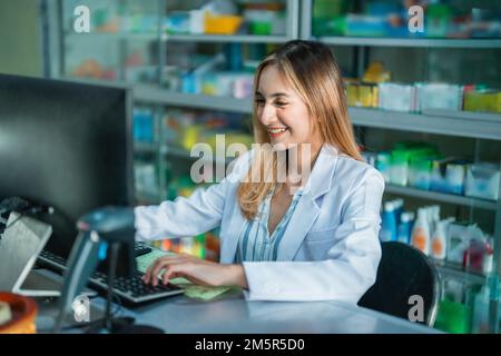 Attraktive Apothekerin in Uniform, die am pc arbeitet Stockfoto