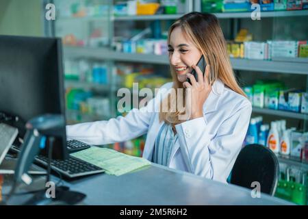 Ein wunderschöner Apotheker, der mit dem Computer beschäftigt ist und Anrufe entgegennimmt Stockfoto