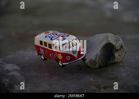 Eine Verkleidung eines rot-weißen Hippie-VW-Wagens (der Käfer war der Typ 1) mit Love and Flower Power 1960er. Stockfoto