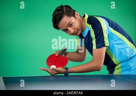 Männlicher Sportler mit Paddel beim Servieren eines Tischtennisspiels Stockfoto