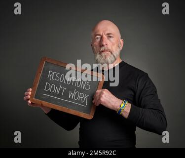 Vorsätze funktionieren nicht - weiße Kreide auf einer Schiefertafel gegen rustikales Holz, das von einem erfahrenen Mann gehalten wird, Zielsetzung und persönliche Entwicklung CO Stockfoto