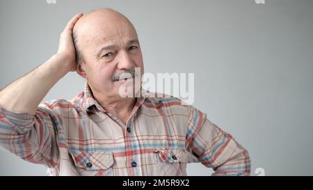 Ein älterer lateinamerikanischer Mann, der versucht, sich an etwas zu erinnern, oder schreckliche Kopfschmerzen hat. Stockfoto