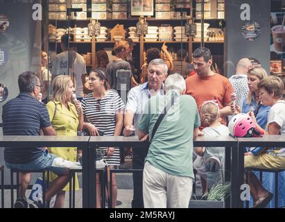 Bukarest, Rumänien - August 2022: Urbane Szene mit einer Gruppe von Menschen, die Eiscreme vor einer Eisdiele in der Altstadt von Buchares essen Stockfoto