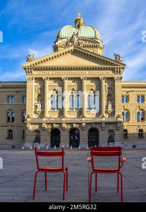 Bern, Schweiz - 12. Juli 2022: Zwei rote Stühle vor dem bundesparlamentgebäude in Bern, Schweiz Stockfoto