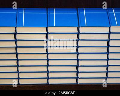 Ein Stapel identischer Kirchenbücher mit blauem Einband und Kreuz auf einem Regal in einer Kirche Stockfoto