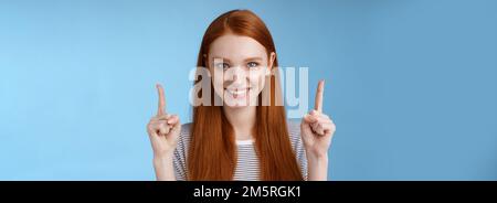 Bestimmt gut aussehende Rothaarige weibliche Schüler geben College endgültige Entscheidung zeigen Nach oben gezogene Zeigefinger sehen selbstbewusst lächelnd weiße Zähne aus Stockfoto