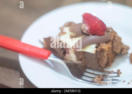 Geburtstagskuchen mit Kerzen in der Form von Nummer 27 auf einem Tisch für ein paar Leute und eine Flasche Wein im Hintergrund, Erwachsenentarif-Konzept Stockfoto