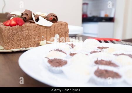 Geburtstagskuchen mit Kerzen in der Form von Nummer 27 auf einem Tisch für ein paar Leute und eine Flasche Wein im Hintergrund, Erwachsenentarif-Konzept Stockfoto
