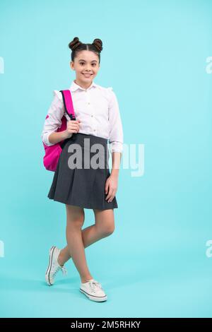 Schulmädchen in Schuluniform mit Schultasche. Schulkind, Teenager-Student mit blauem isoliertem Hintergrund. Stockfoto