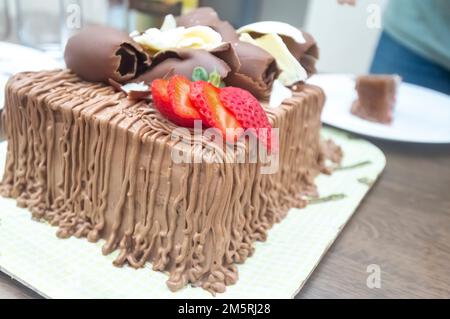 Geburtstagskuchen mit Kerzen in der Form von Nummer 27 auf einem Tisch für ein paar Leute und eine Flasche Wein im Hintergrund, Erwachsenentarif-Konzept Stockfoto