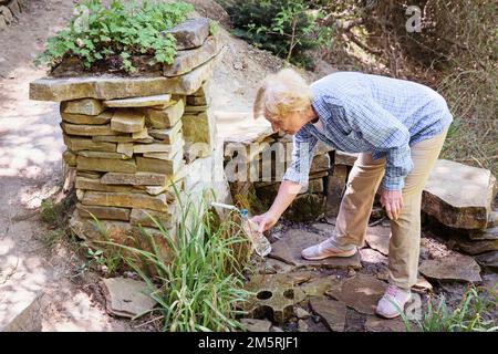 Ältere Frau, die sich nach einem aktiven Waldspaziergang ausruht Stockfoto
