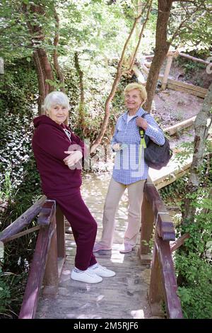 Zwei Seniorinnen, die Urlaub im Freien verbringen und im Wald spazieren gehen Stockfoto