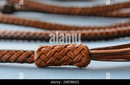 Ein komplizierter, langer Lederknoten, der von einem einzelnen Lederstrang in einem über zwei, unter zwei Mustern, am Ende der handgeflochtenen Lederhandschuhe gebunden ist Stockfoto