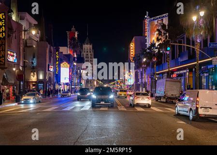 Autos, die nachts zwischen beleuchteten Theatern und Gebäuden auf der Straße unterwegs sind Stockfoto