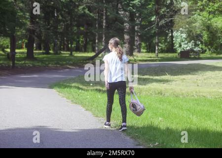 Mädchen im Schulalter mit kleinen Rucksackspaziergängen im Sommerpark. Stockfoto