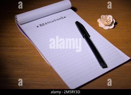 RESOLUTION ist auf einem Notizblock oder Buch zusammen mit einem Stift auf dem Tisch geschrieben. Stockfoto