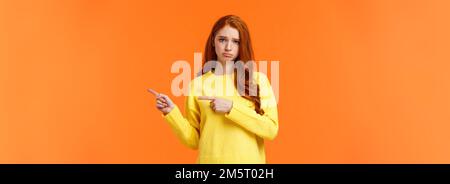 Schmollen Moody und traurig Süße rothaarige Freundin nach rechts und runzelte die Stirn, stehend unglücklich mit schlechter Laune, Neid jemand, betteln Freund Buch Stockfoto