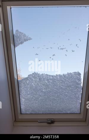 Blick auf das Innere des schneebedeckten Dachfensters vom Zimmer, das am frostigen Wintertag mit Schnee bedeckt war. Schweden. Stockfoto