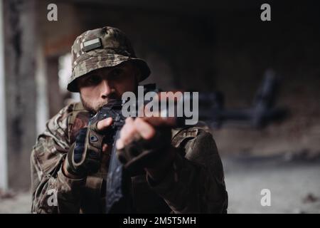 Das ukrainische Militär verteidigt seine Positionen. Soldat im Krieg, mit Waffen in der Hand, zielt auf den Feind Stockfoto