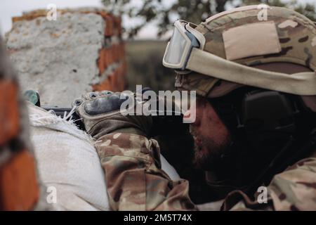 Das ukrainische Militär verteidigt seine Positionen. Soldat im Krieg, mit Waffen in der Hand, zielt auf den Feind Stockfoto