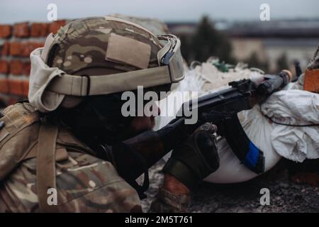 Das ukrainische Militär verteidigt seine Positionen. Soldat im Krieg, mit Waffen in der Hand, zielt auf den Feind Stockfoto