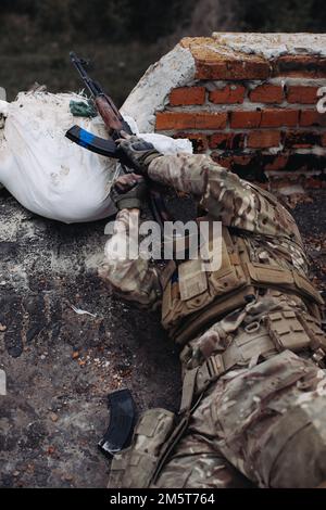 Das ukrainische Militär verteidigt seine Positionen. Soldat im Krieg, mit Waffen in der Hand, zielt auf den Feind Stockfoto