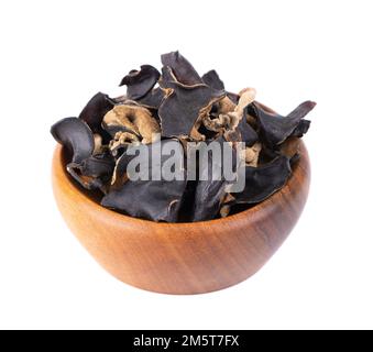 Trockener schwarzer Pilz in Holzschüssel, isoliert auf weißem Hintergrund. Chinesischer schwarzer Pilz oder Baum schwarzer Muer Pilz. Auricularia polytricha Stockfoto