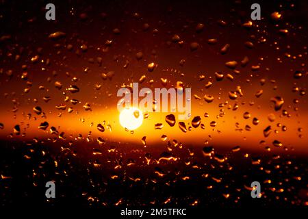 Tropfen auf das Glas mit Sonnenlicht. Tröpfchen und Dämmerung. Wasser an transparenter Oberfläche Stockfoto