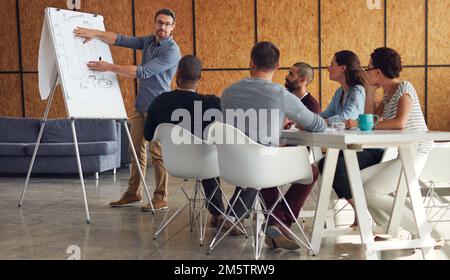 Der kreative Prozess. Ein reifer Mann, der Kollegen in einem Büro eine Whiteboard-Präsentation gibt. Stockfoto