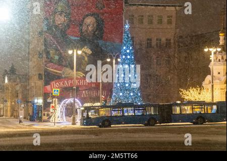 Moskau, Russland - 7. Dezember 2022: Blauer Bus fährt im Winter in einem kalten und verlassenen Moskau eine verschneite Straße hinunter Stockfoto