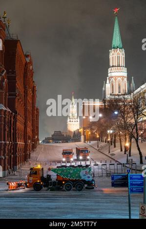 Moskau, Russland - 7. Dezember 2022: Das Auto KAMAZ räumt in einer kalten Winternacht Schnee von der Straße in der Nähe des Kremls und des Roten Platzes Stockfoto