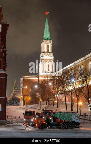 Moskau, Russland - 7. Dezember 2022: Das Auto KAMAZ räumt in einer kalten Winternacht Schnee von der Straße in der Nähe des Kremls und des Roten Platzes Stockfoto