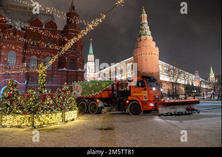 Moskau, Russland - 7. Dezember 2022: Das Auto KAMAZ räumt in einer kalten Winternacht Schnee von der Straße in der Nähe des Kremls und des Roten Platzes Stockfoto