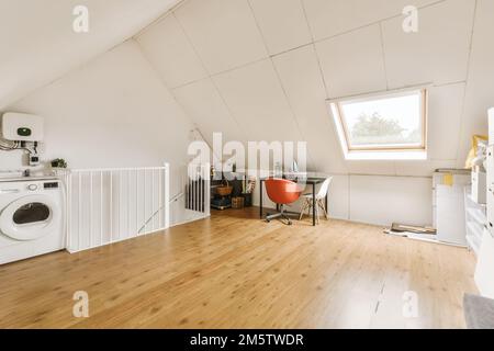 Ein Zimmer mit Holzfußboden und eine Waschmaschine in der Ecke, neben einer offenen Tür, die zu einem Fenster führt Stockfoto