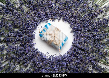 Flache Laienzusammensetzung mit Seifenleiste und Lavendelblumen auf weißem Hintergrund. Speicherplatz kopieren Stockfoto