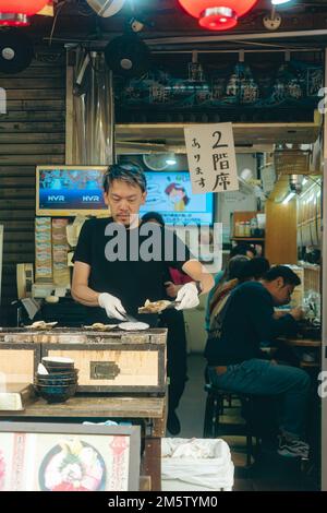 Leute essen in kleinen Restaurants auf dem Tsukiji Markt Stockfoto