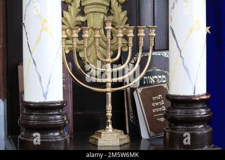 SAFED, ISRAEL - 8. MAI 2011: Dies ist eine Menora unter religiösen Büchern auf einem Regal in der Synagoge. Stockfoto