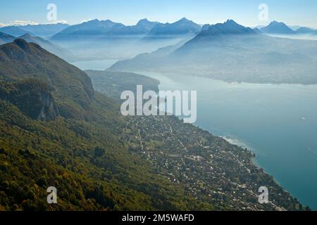 Blick vom Gipfel des Mont Baron über das Dorf Veyrier-du-Lac nach Lac dAnnecy im Herbstnebel zu den Gipfeln der Savoyen Alpen, See von Stockfoto