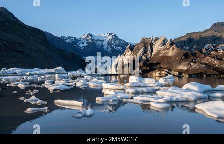 Reflexion in der Gletscherlagune Svinafellslon mit Eisschollen, der Gletscherzunge Svinasfellsjoekull, dem gletscherbedeckten Berggipfel Hrutfjallstindar in der Stockfoto