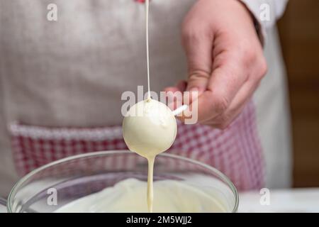 Bedecke den Kuchen mit geschmolzener weißer Schokolade und Schokokuchen-Pops mit Streuseln Stockfoto