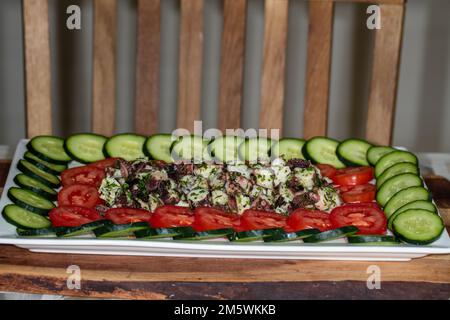 Große Platte mit frischem Salat mit Gurke, Tomate und zentraler Mischung (Meeresfrüchte?). Gesunde Vorspeise oder Catering-Aufstrich. Stockfoto