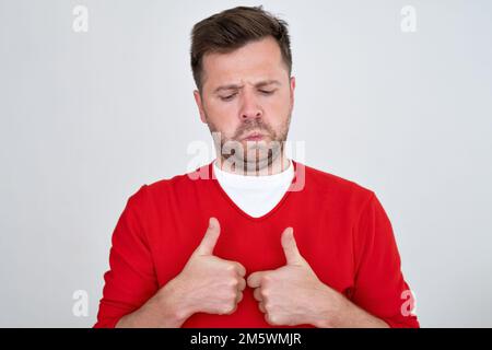 Junger Mann, der eine gute Daumen-hoch-Geste mit traurigem Gesicht macht. Stockfoto